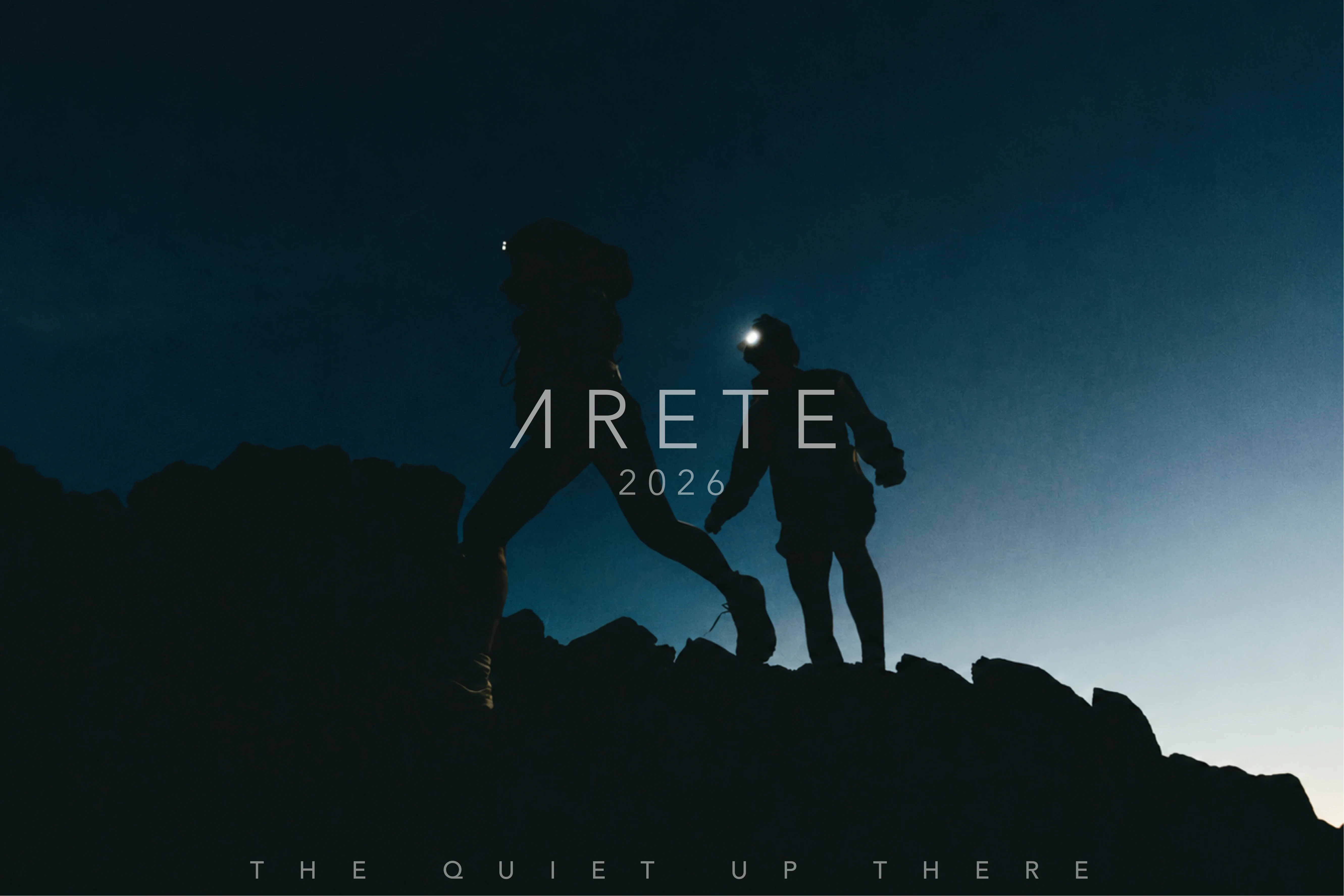 Two climbers stand on a night summit beneath ARETE 2026 and The Quiet Up There