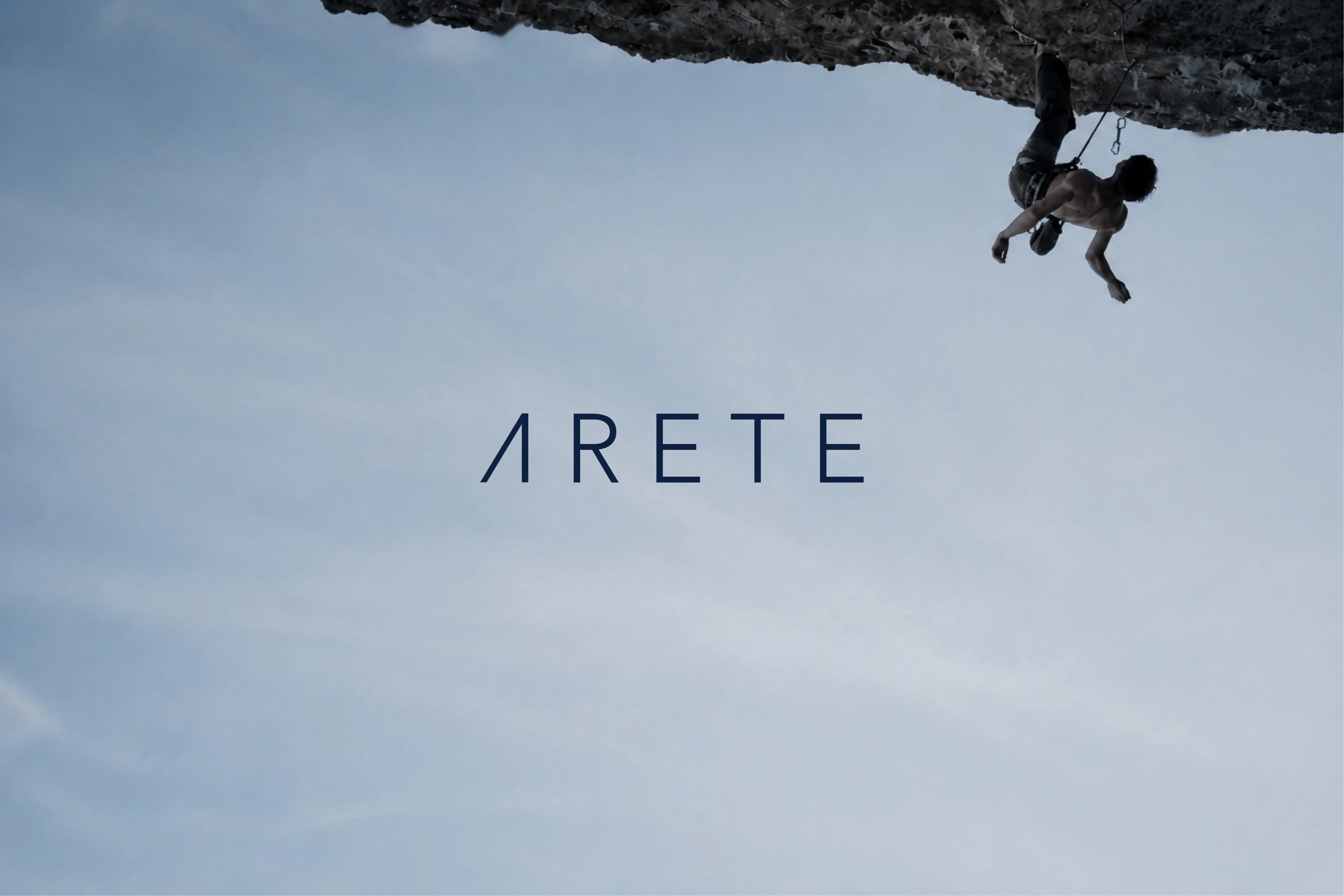 A climber hangs above a rock face beneath the ARETE wordmark